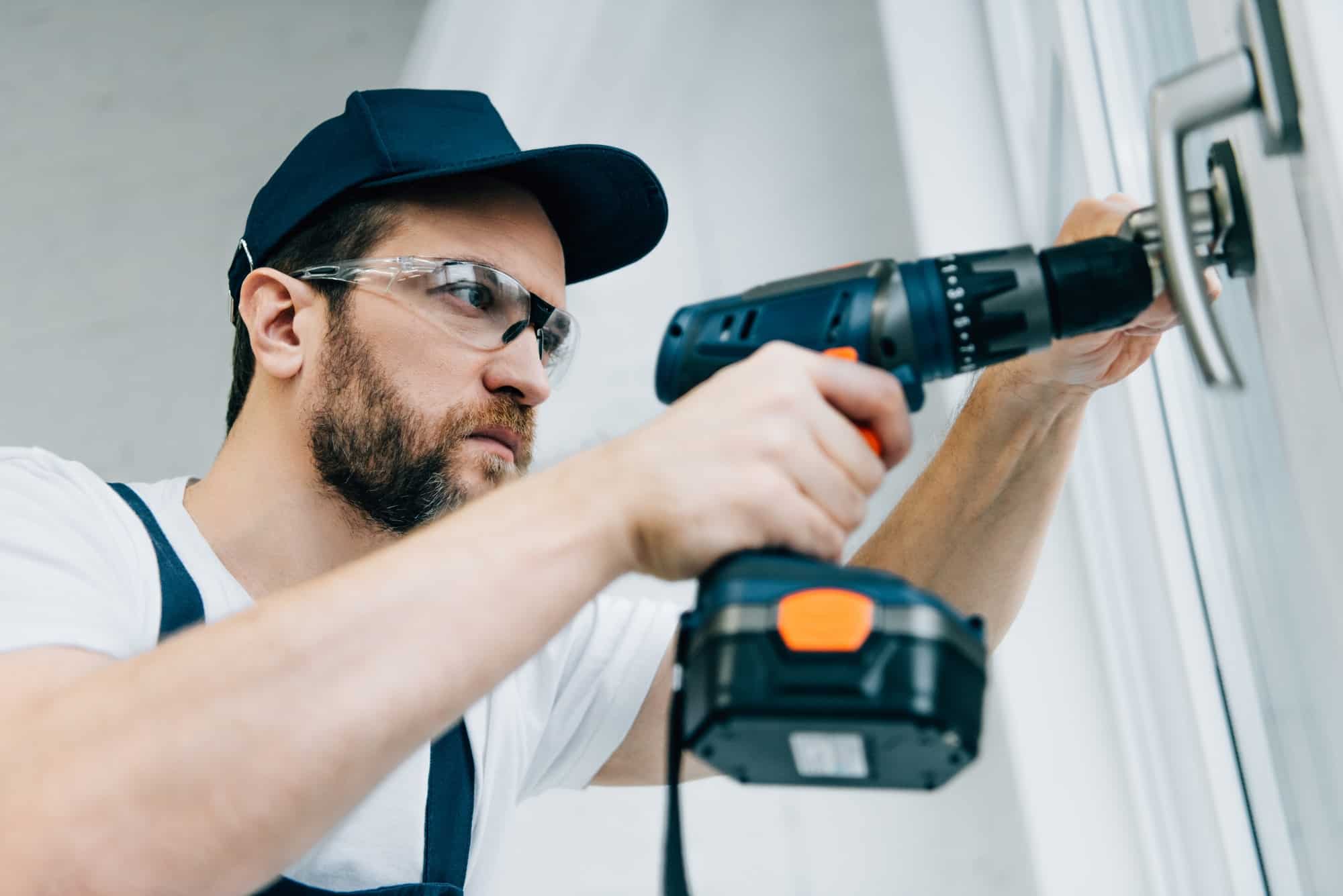 adult-repairman-in-goggles-fixing-window-handle-by-electric-drill.jpg